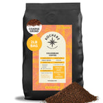 A 2-pound bag of Kochere Coffee Colombian Medellin Single Origin Medium Roast, with dried orange and berry notes and an orange label from Kochere Coffee Company. Some coffee is spilled in front.