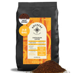 A 2-pound bag of Kochere Coffee Costa Rican Alajuela Medium Light Roast by Kochere Coffee Company, featuring sweet apple and raisin notes, with coffee grounds spilled in front.