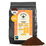 A 5lb bag of Kochere Coffee Colombian Medellin Single Origin Medium Roast, drip grind, with dried orange and berry notes; Fairtrade certified by Kochere Coffee Company. Ground coffee is piled in front.