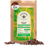 A 12oz bag of Kochere Coffee Brazilian Santos Medium Roast by Kochere Coffee Company, featuring smooth, elegant cocoa notes and a green and yellow label, is surrounded by whole coffee beans.