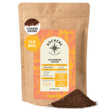 A 1lb bag of Kochere Coffee Colombian Medellin Single Origin Medium Roast, coarse grind, with ground coffee spilled in front. The label notes dried orange and berry flavors and emphasizes it's roasted to order for freshness. [1lb][coarse grind]