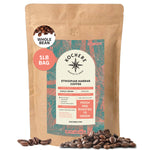A 1lb bag of Kochere Coffee Ethiopian Harrar Natural Medium Roast by Kochere Coffee Company, featuring organic beans scattered in front. The label highlights single origin, fresh roasted to order, with fruity blueberry and dark chocolate notes.