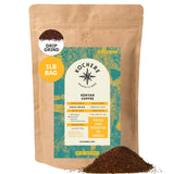 A 1lb bag of Kochere Coffee Kenyan Nyeri Embu AB Medium-Light Roast by Kochere Coffee Company, fruity and balanced, drip grind, with a teal and yellow label and a small pile of ground coffee in front.