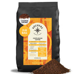 A 2-pound bag of Kochere Coffee Costa Rican Alajuela Medium Roast by Kochere Coffee Company, featuring sweet apple and raisin notes, sits upright with some coffee grounds spilled in front.[2LB][coarse grind]