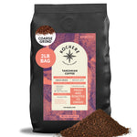 A 2lb bag of Kochere Coffee Company’s Tanzanian Mbeya AB, medium-light roast with pear, floral, and jasmine notes (coarse grind), is shown with fresh ground coffee. Label highlights single origin and roasted to order freshness.