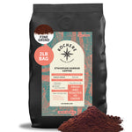 A 2lb bag of Kochere Coffee Ethiopian Harrar Natural Medium Roast (fine grind) with spilled grounds in front. The label shows its fruity, blueberry, and dark chocolate notes—ideal for those who love premium single origin coffee.