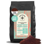 A 2lb bag of Kochere Coffee Ethiopian Sidamo Natural Medium-Light Roast, by Kochere Coffee Company, with milk chocolate and fruity notes, sits beside a pile of ground coffee. The label highlights its fresh roast and single origin.[2LB][fine grind]