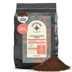 A 5lb bag of Kochere Coffee Company’s Ethiopian Harrar Natural Medium Roast, featuring fruity blueberry and dark chocolate notes, with coarse ground organic beans shown in a pile in front.
