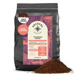 A 5lb bag of Kochere Coffee Tanzanian Mbeya AB Medium-Light Roast by Kochere Coffee Company, single origin with pear, floral, and jasmine notes, is displayed with a mound of floral coffee grounds in front.