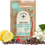A bag of Kochere Coffee Company’s Horn of Africa Reserve Signature Espresso Blend, a medium-dark roast, is shown with coffee beans, fruits, and flowers arranged in the foreground.