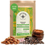 Bag of Kochere Single Origin Brazilian medium roast coffee, displayed with raw almonds, fresh lemongrass, and dark chocolate to represent its balanced, aromatic flavor profile. [12 oz][Whole Bean]