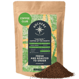 A bag of Kochere Coffee Company’s Safari "Coffee of the Month" Club—fresh roasted single origin coffee—sits beside a pile of grounds, in green and yellow packaging. Ideal for your next subscription or monthly pick!.
