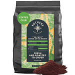 A black bag of Kochere Coffee Company’s Safari "Coffee of the Month" Club—fresh roasted, single-origin coffee with a green label—sits next to ground coffee, highlighting freshness and ideal for any subscription or enthusiast.[5LB][fine grind]