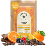 A bag of Kochere Coffee Company Colombian Medellin Single Origin Medium Roast is surrounded by chocolate, orange slices, blueberries, and coffee beans to highlight its dried orange and berry flavor notes.