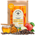 A 12 oz bag of Kochere Coffee Company’s Costa Rican Alajuela Medium Roast is displayed with coffee beans, a red apple, raisins, and caramel pieces, highlighting its sweet apple and raisin notes.[12 oz][Whole Bean]