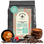 Bag of Kochere Single Origin Ethiopian Sidamo medium-light roast coffee, displayed with rich caramel, fresh berries, and dark chocolate to represent its decadent flavor profile. [5LB][Whole Bean]