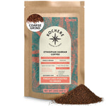 A 12oz bag of Kochere Coffee Company’s Ethiopian Harrar Natural Medium Roast, featuring fruity, berry, and dark chocolate notes, labeled coarse grind, stands upright with a small pile of ground coffee beside it.[12 oz][coarse grind]