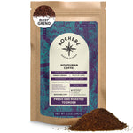 A brown bag of Kochere Coffee Company's Honduran Marcala Organic Medium Roast, 12 oz, labeled single origin with caramel, spice, and brown sugar notes, is shown with a pile of ground coffee in front.