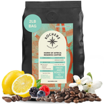 Kochere Horn of Africa Reserve medium-dark roast coffee, displayed with fresh lemons, berries, and white blossoms to represent its flavor profile. [2LB][whole bean]