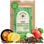 Bag of Kochere Single Origin Ugandan medium roast coffee, displayed with rich caramel, fresh lemons, and crisp red apples to represent its sweet and vibrant flavor profile. [12 oz][Whole Bean]