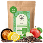 Bag of Kochere Single Origin Ugandan medium roast coffee, displayed with rich caramel, fresh lemons, and crisp red apples to represent its sweet and vibrant flavor profile. [1LB][Whole Bean]