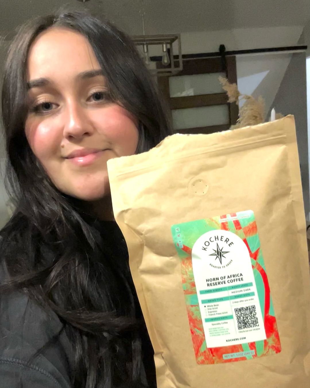 A person holding up a large brown bag labeled “Horn of Africa Reserve Coffee” from Nochere Coffee.