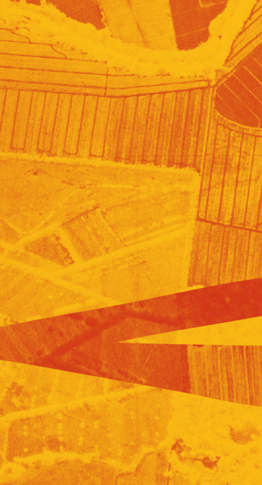 Aerial view of agricultural fields in orange and yellow tones with linear patterns and geometric shapes.