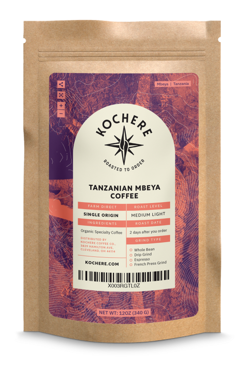 A package of Kochere Coffee Company's Tanzanian Mbeya Coffee - Single Origin - Medium Light Roast beans, labeled with details like origin, medium-light roast level, and net weight, against a striped background.